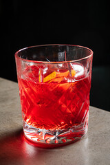 Reflecting elegance, a crystal glass holds a vibrant red cocktail adorned with citrus twists