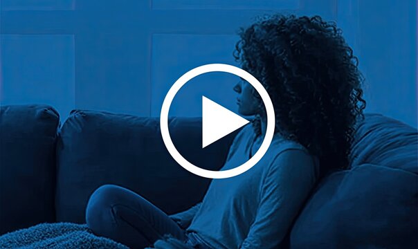 Woman seated on a couch, profile view, play button overlay