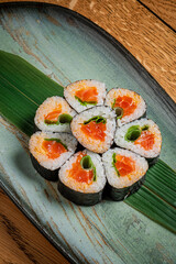 Sushi rolls with fresh salmon and avocado rest elegantly on a leaf-patterned dish