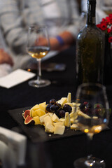 Cheese board with grapes and figs served with white wine at a tasting table