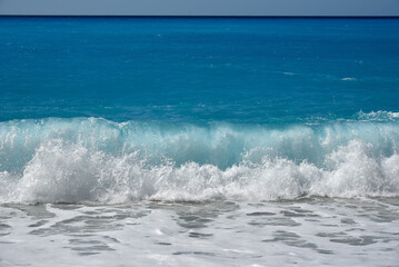 An incoming foaming wave on the pebble beach. Rough sea.