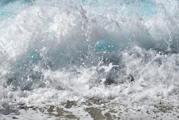 Close-up of a foaming wave breaking on the pebble beach. Rough sea. 