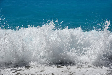 Close-up of a foaming wave breaking on the pebble beach. Rough sea. 