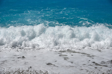 Foaming wave breaking on the pebble beach. Rough sea.