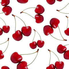 Bright red cherries with green stems scattered on a plain white backdrop