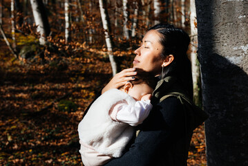 Mother Cradles Her Baby Girl in a Serene Forest Setting During a Sunny Day