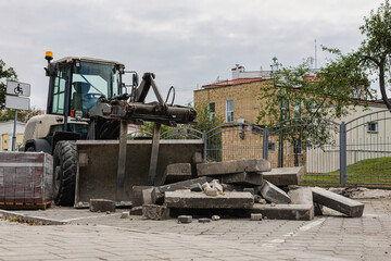 Construction machinery moves large concrete slabs in urban renovation effort during cloudy day