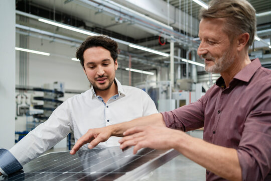 Young businessman with manager explaining solar panel at factory