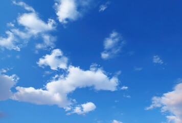 Obraz premium Azure sky filled with fluffy, white cumulus clouds scattered across the clear blue expanse, some touched by soft pink hues on the horizon