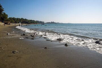 Beachfront with Waves, Foamy Shoreline, and People Enjoying the Scenic Coastline