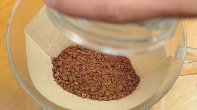 ペーパードリップでコーヒーを淹れる工程。ドリッパーに中挽きの豆を入れ1回目の蒸らしの湯を注ぐ男性。