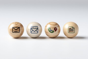 Four light wood spheres, each with a contact icon mail, email form, phone with map pointer, and document. White background. Studio lighting