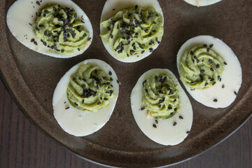 close up of green rotten deviled eggs served on a dark plate, spooky halloween party appetizer with creepy coloring and creamy filling