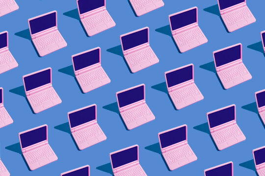 Pink laptops arranged in a seamless pattern on blue background