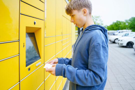 Boy with ticket standing in front of parcel locker