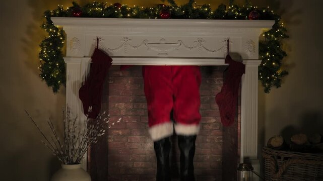 4k: Father Christmas coming down the chimney on Christmas Eve. Santa brings a sack of presents and gifts - Stock Video Clip Footage