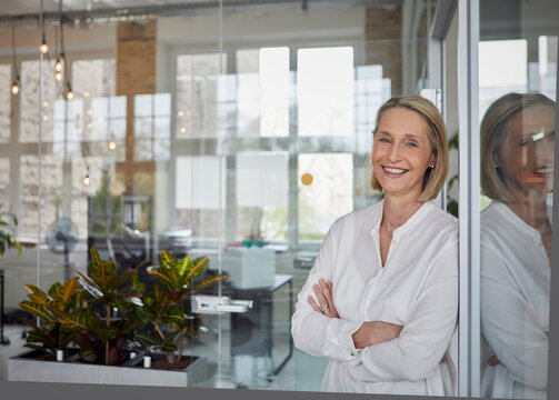 Businesswoman smiling with arms crossed in modern office