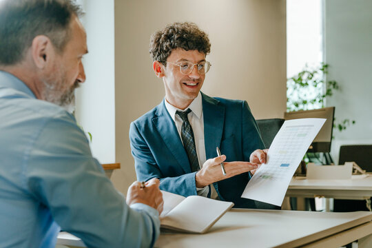 Consultant presenting financial document to client at office desk