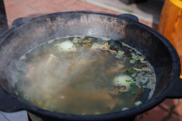 Enjoy a bowl of delicious, steaming broth simmering in a pot, perfect for comfort and warmth