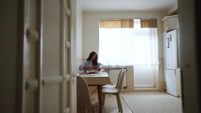 Focused woman enjoying a meal at a bright kitchen table during the morning