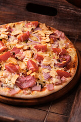 Pizza with ham, salami, cherry tomatoes and mozzarella cheese. Rustic wooden background. Soft focus. Close up.	