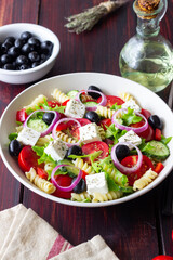 Greek pasta salad with feta cheese, tomatoes, onion, cucumbers, peppers and olives. Healthy eating. Vegetarian food.