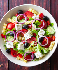 Greek pasta salad with feta cheese, tomatoes, onion, cucumbers, peppers and olives. Healthy eating. Vegetarian food.