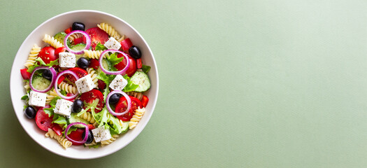 Greek pasta salad with feta cheese, tomatoes, onion, cucumbers, peppers and olives. Healthy eating. Vegetarian food.