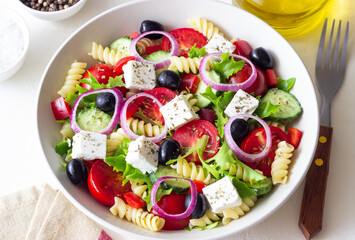 Greek pasta salad with feta cheese, tomatoes, onion, cucumbers, peppers and olives. Healthy eating. Vegetarian food.