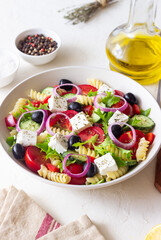 Greek pasta salad with feta cheese, tomatoes, onion, cucumbers, peppers and olives. Healthy eating. Vegetarian food.
