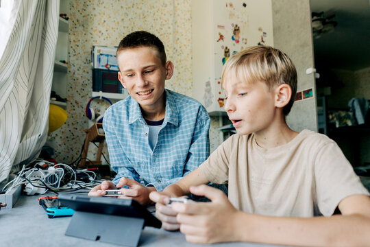 Two teenage brothers compete in computer games on a tablet.
