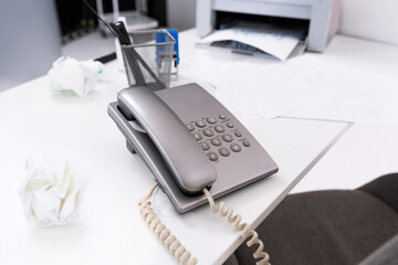 Office desk with a corded telephone amidst paperwork and office supplies highlighting a busy...