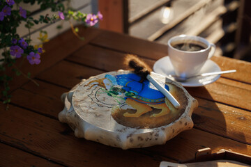 A Beautiful Artistic Wooden Plate Placed Alongside a Brush and a Cozy Cup of Coffee on a Table
