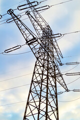 Electricity Transmission Tower with Context on Rising Electricity Costs in Poland.  Photo of a tall metal electricity pylons with multiple power lines extending across a partly cloudy sky