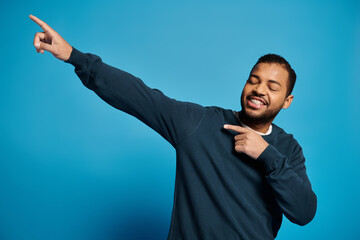 Young man in blue jumper showcases confident pose in vibrant studio setting