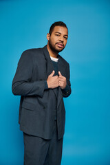 Stylish young man poses confidently in blue jumper against vibrant studio backdrop