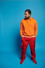 Vibrant autumn fashion with a young man in casual orange attire against a blue backdrop