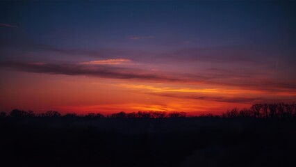 Obraz premium A serene and beautiful sunset over a forest silhouette, featuring a soft and warm gradient of orange and yellow in the evening sky for a peaceful background