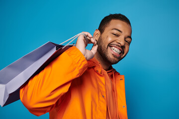 Vibrant autumn fashion showcased by young man in studio with blue backdrop
