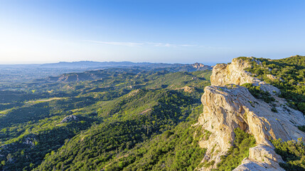 Naklejka premium Breathtaking mountain landscape with rocky cliffs, lush greenery, and clear blue sky, evoking sense of tranquility