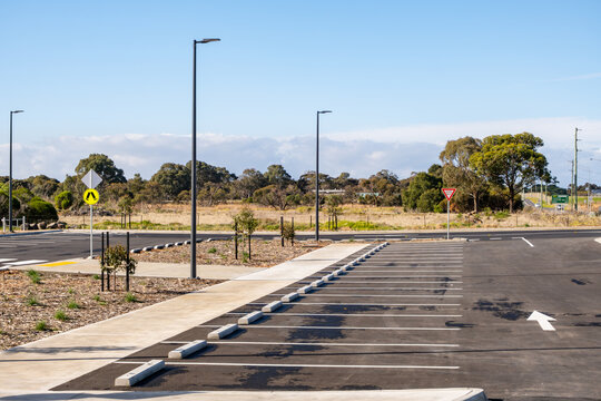 Empty parking lot with marked bays, street lamps, and wheel stops in a suburban Melbourne, Australia. Concept of urban infrastructure, transportation facilities, and modern public space planning