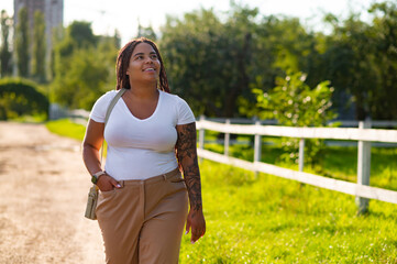Plus size female with tattoo arm enjoying walk along pathway