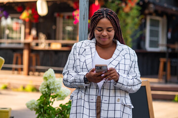 African American plus size woman looking at smartphone outdoors