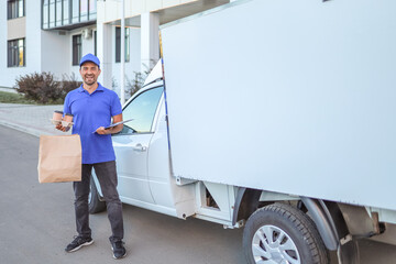 man in baseball cap and uniform holding bag of food and coffee cups near van customer service concept