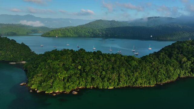 Aerial view of islands covered in lush green vegetation surrounded by turquoise waters with boats sailing, creating a beautiful contrast, Paraty, State of Rio de Janeiro, Brazil.