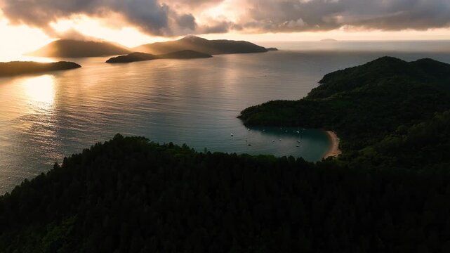 Aerial view of islands covered in dense forest meeting the ocean under a dramatic sky with golden sunlight, Paraty, State of Rio de Janeiro, Brazil.