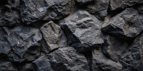 The rock wall texture of rough dark basalt stones in dramatic natural detail