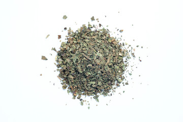 pile of dried and chopped basil spice on white background, top view