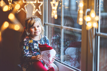 Little preschool girl holding cup Santa Claus boot with gift called Nikolausstiefel in German....