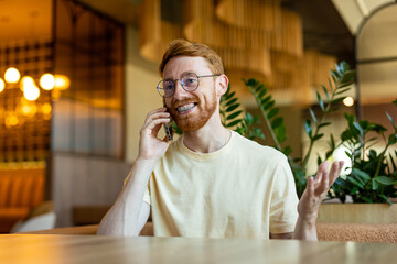 Bearded redhead man holding phone to ear at restaurant